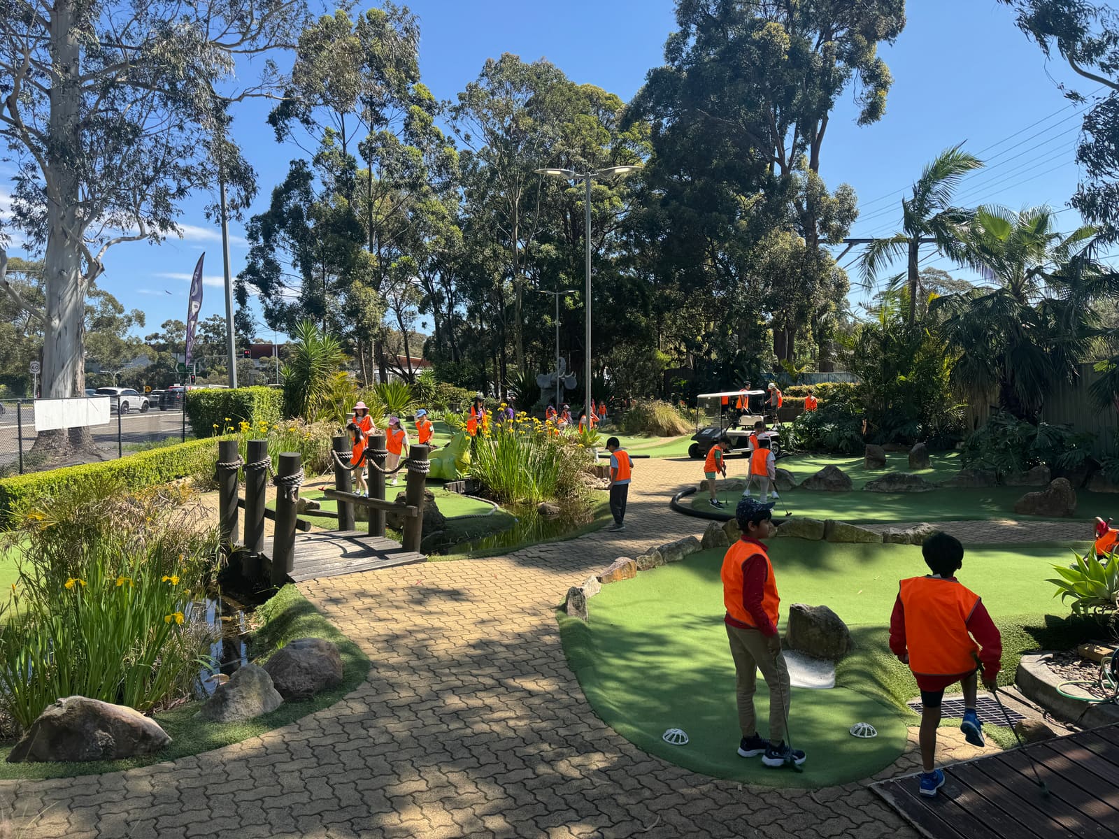 A school group in hi-vis vests playing mini golf at City Golf Gordon